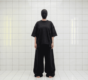 Moteris modelis su juoda kauke devinti TEMPO_WERK juodus oversized marškinėlius ir ypač plačias kelnes